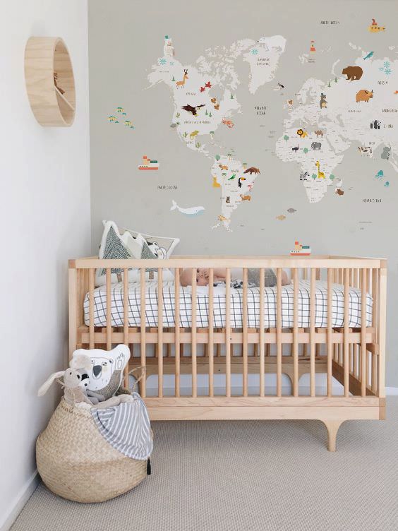 دکوراسیون اتاق خواب نوزاد با تم ماجراجویی و جهانگردی که دارای تخت نوزاد چوبی و کاغذ دیواری با طرح نقشه جهان می باشد